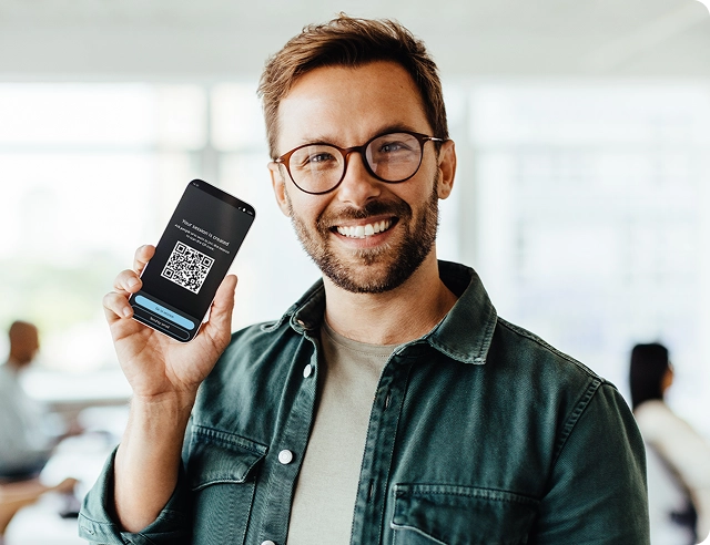 Усмихнат мъж, държащ смартфон, на екрана на който се вижда QR код за присъединяване към Vasco Audience.
