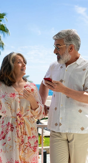 Двама възрастни хора, държащи устройства Vasco V4, разговарят помежду си и демонстрират пет различни опции за скорост на възпроизвеждане.