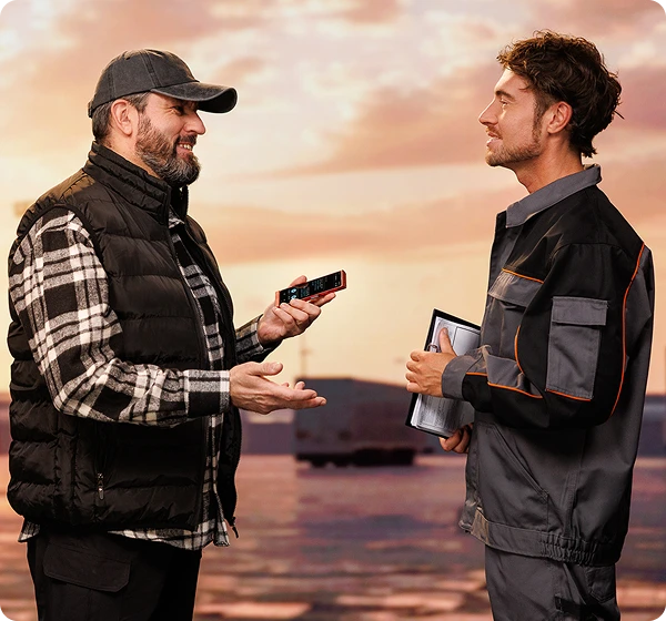 Двама мъже разговарят помежду си; шофьорът на камиона държи Vasco Translator V4, а човекът отсреща, който изглежда е складов работник, държи документи. Те общуват, използвайки Vasco Translator.